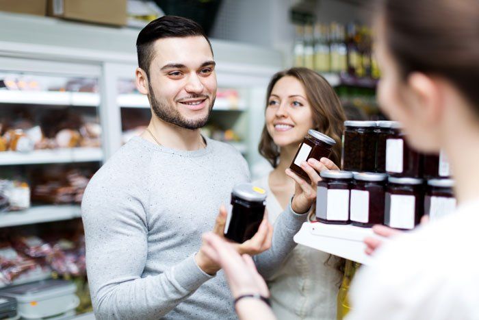 Customer choosing specialty jam in a gourmet grocery store