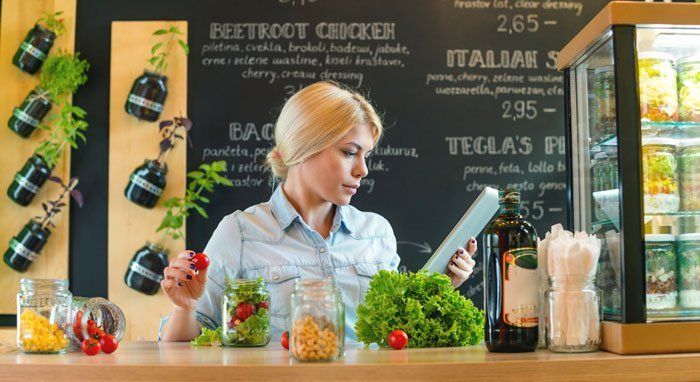 Retailer making salad, watching recipe on iPad